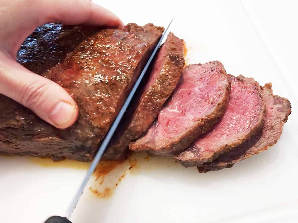 Slicing flat iron steak with a chef's knife. 