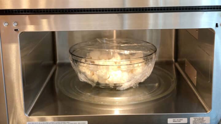 A bowl with cauliflower florets in microwave.