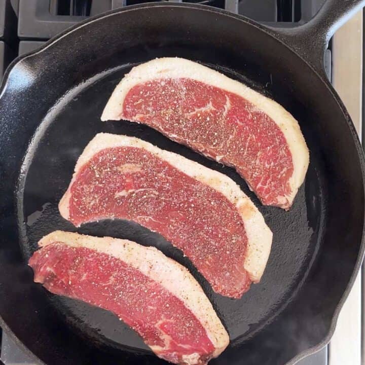 Cooking the steaks on the first side.