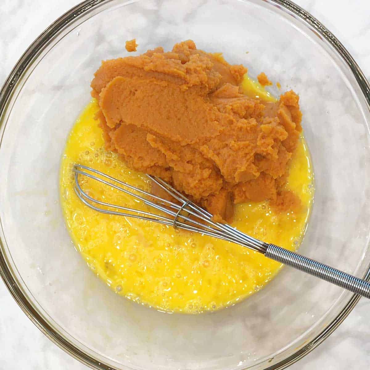 Eggs and pumpkin puree in a bowl. 