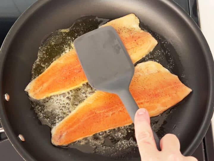 Pressing on the trout with a spatula.