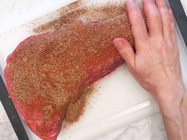 Rubbing the tri-tip with spices.