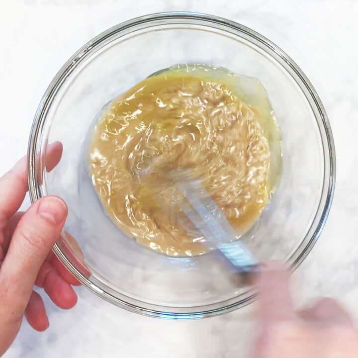 Mixing tahini sauce ingredients in a bowl.