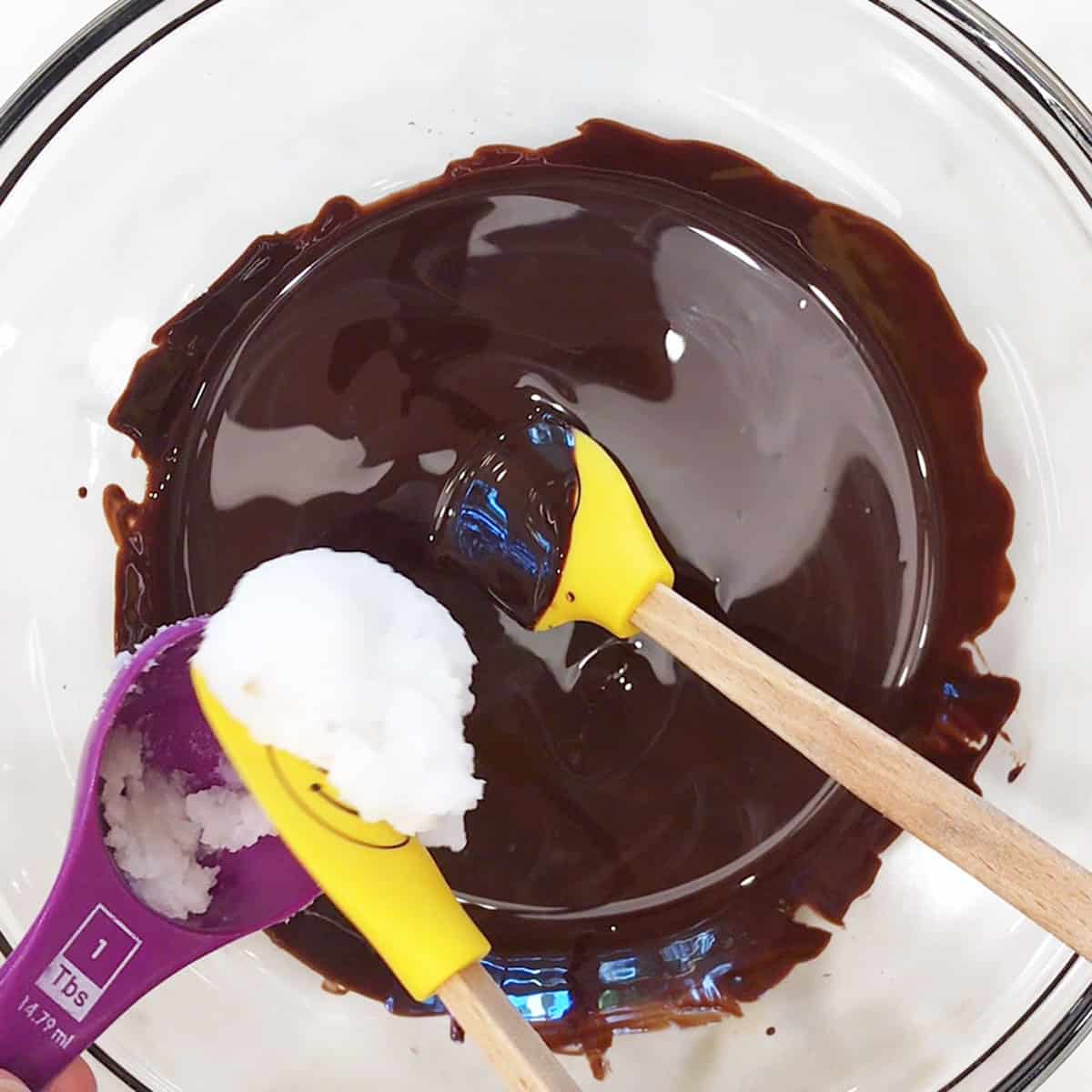 Adding coconut oil to melted chocolate. 