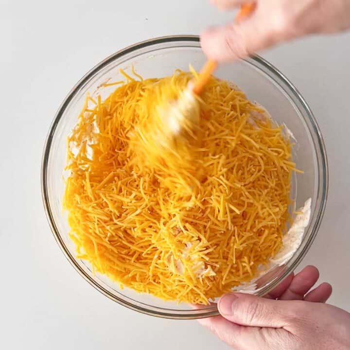 Adding shredded cheese to the bowl.