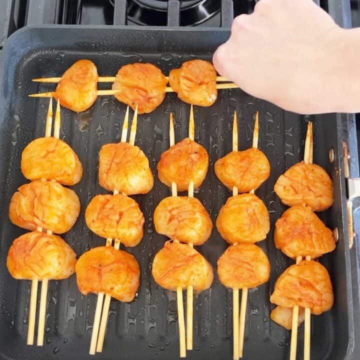 Placing the scallops on the grill.