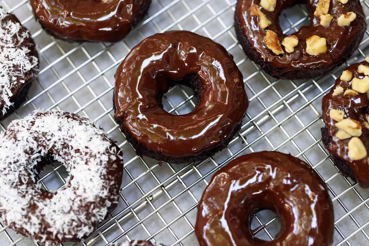 Keto donuts topped with a chocolate glaze, shredded coconut, and chopped nuts. 