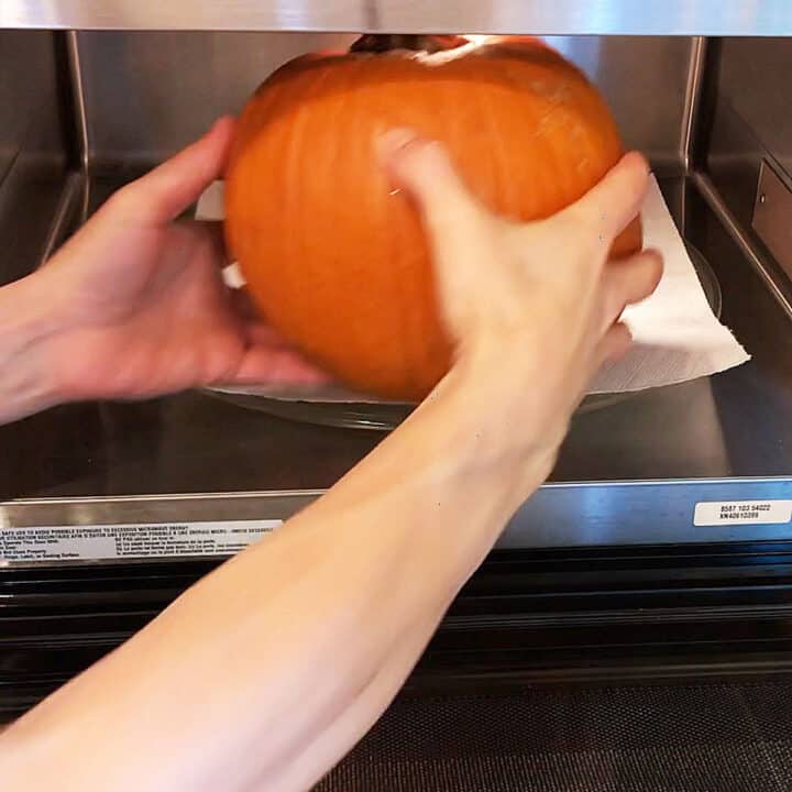 Placing the pumpkin in the microwave.
