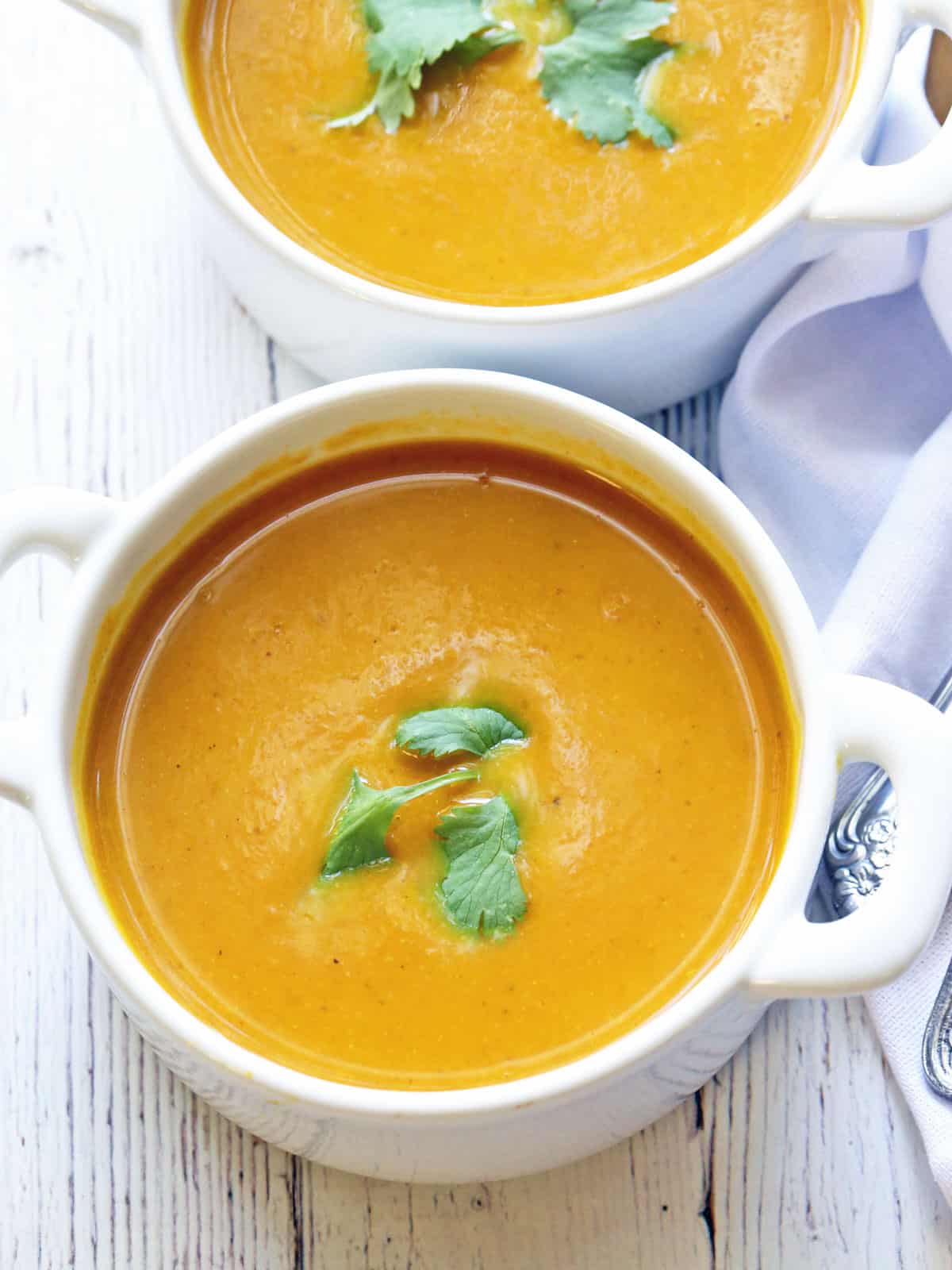 Pumpkin curry soup served in white bowls. 