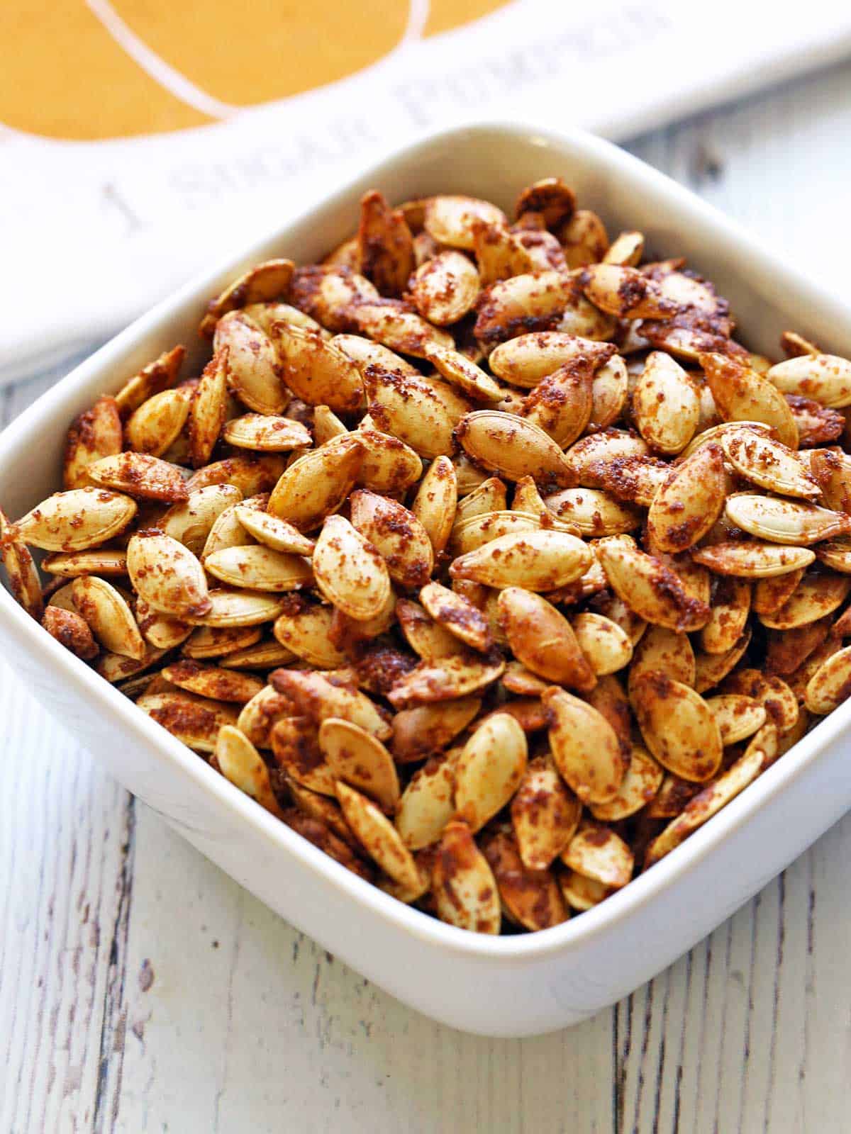 Roasted pumpkin seeds in a white bowl. 