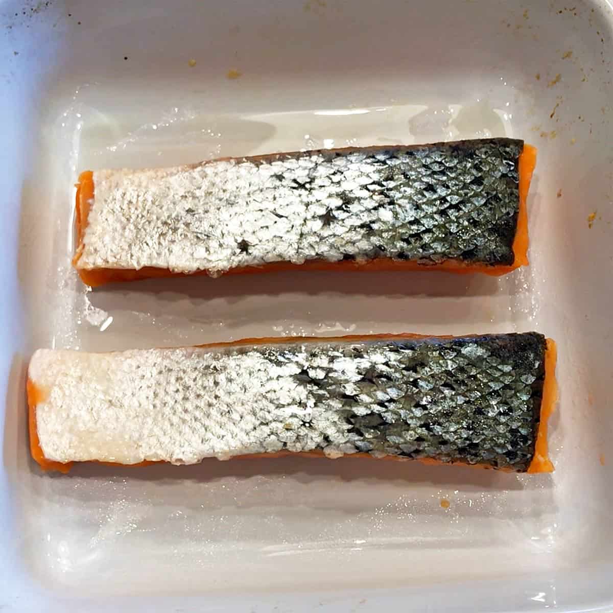 Two salmon fillets in a baking dish. 