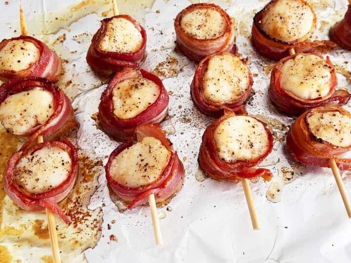 Bacon-wrapped scallops are ready on the baking sheet.