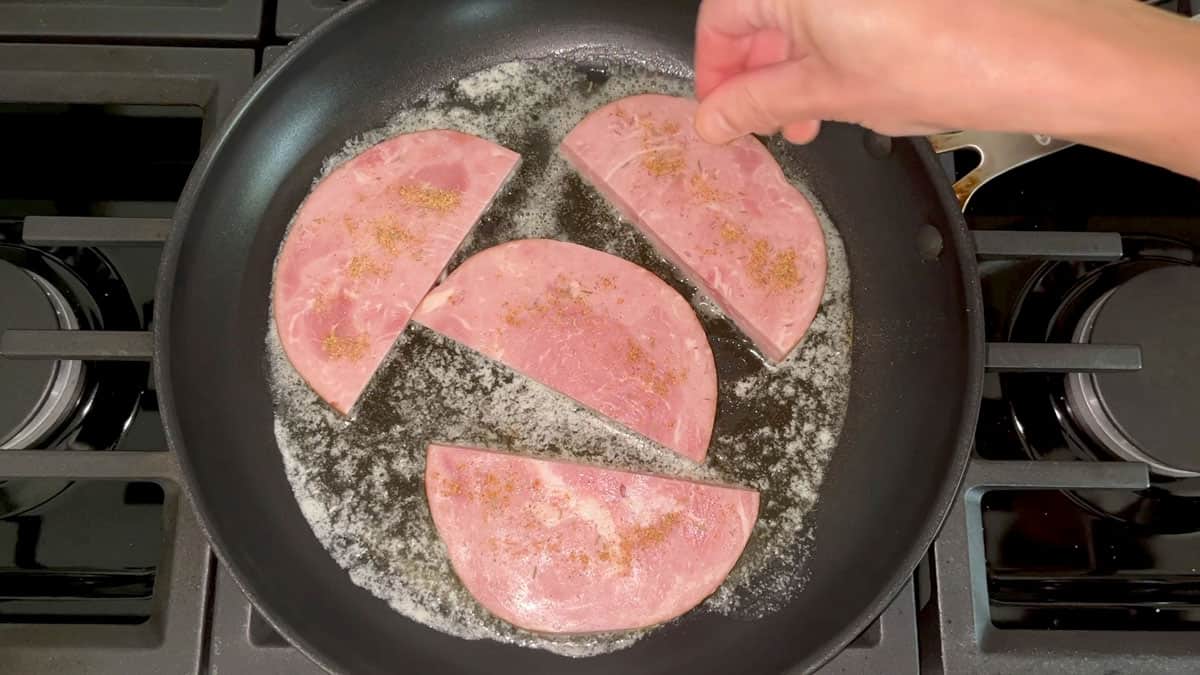 Seasoning ham steaks in the skillet. 