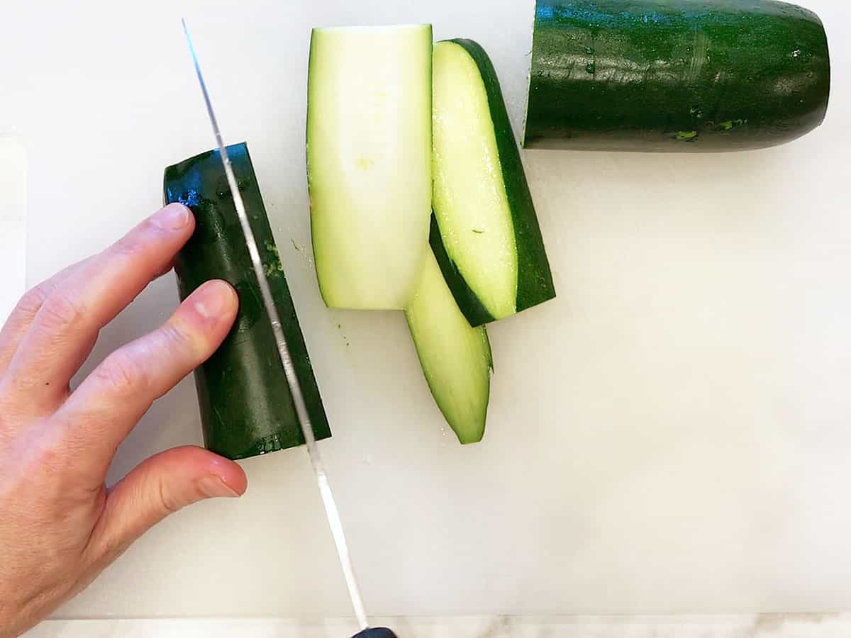 Slicing zucchini on a cutting board. 