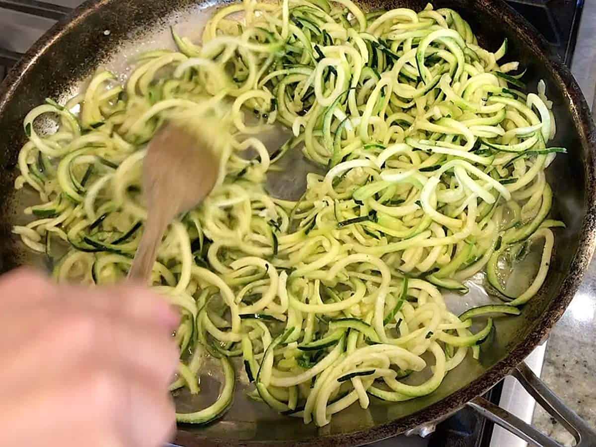 Stirring zoodles in skillet. 