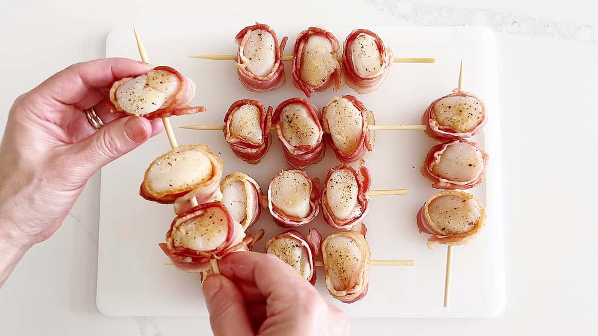 Threading the wrapped scallops on skewers. 
