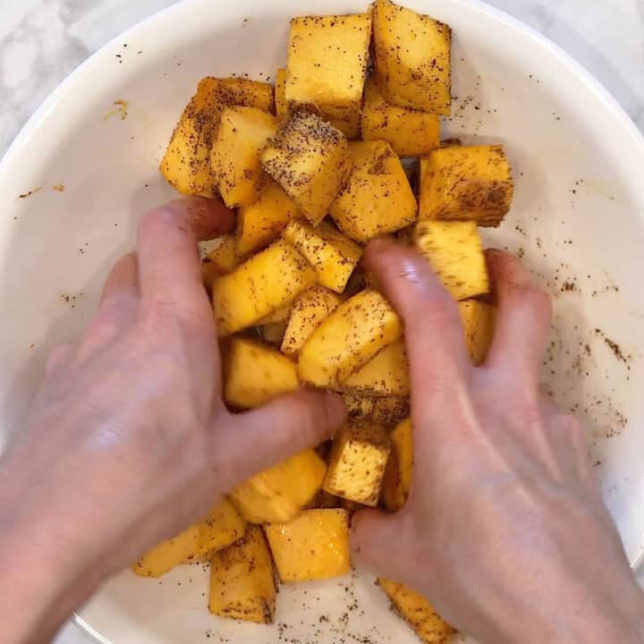 Coating the pumpkin chunks in oil and spices.