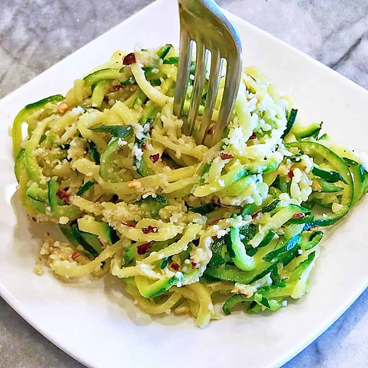 Zucchini noodles are ready and served on a white plate. 