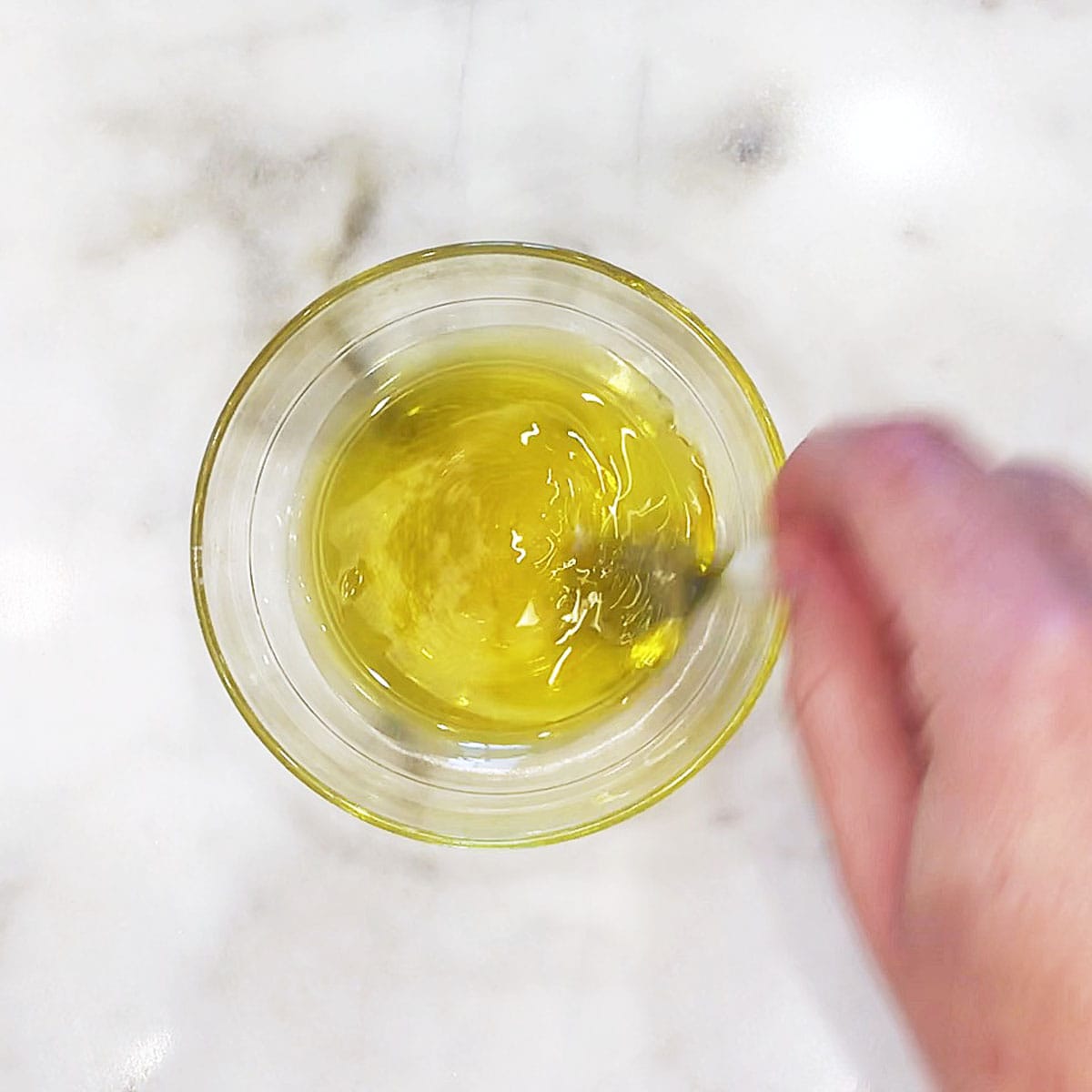 Mixing olive oil and vinegar in a small bowl.