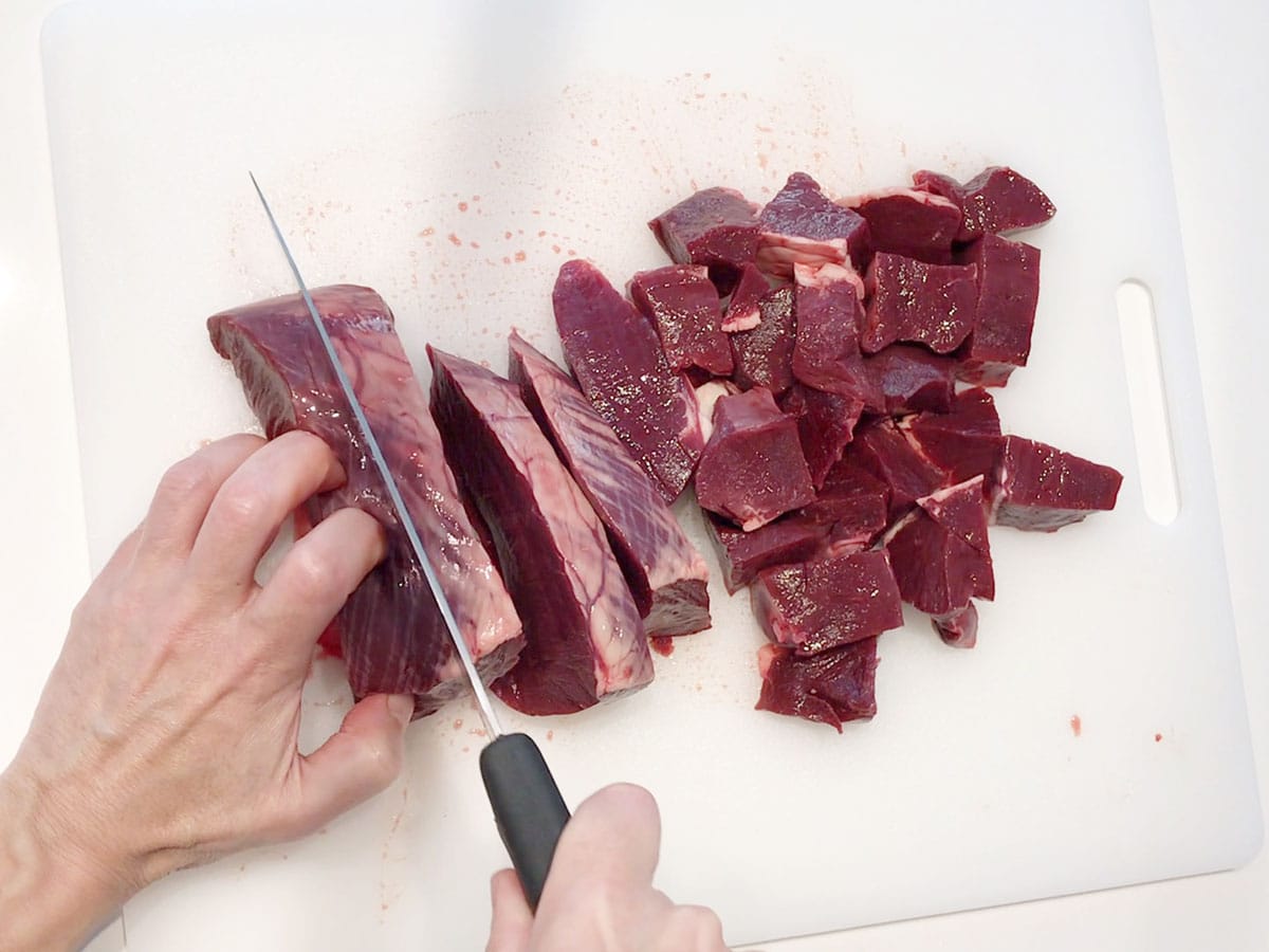 Cutting a beef heart into cubes.
