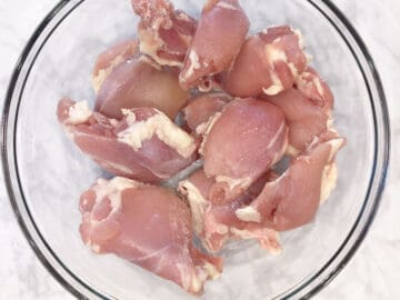 Raw boneless chicken thighs in a bowl. Fat was not trimmed.