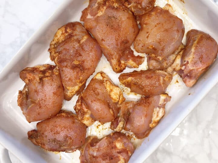Different sizes of boneless chicken thighs arranged in a baking dish.