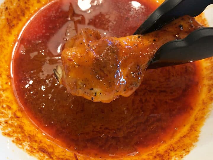 Dipping a chicken wing in buffalo sauce.