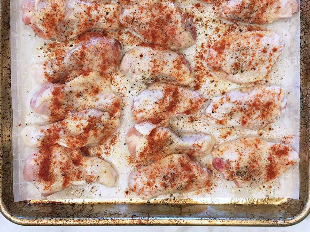 Seasoned raw wings on a baking sheet.