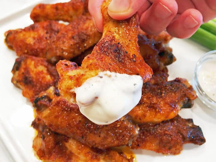 THe buffalo wings are served, dipped in blue cheese sauce.