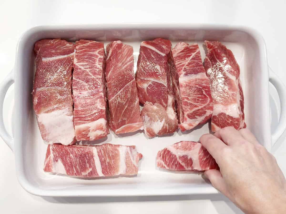 Arranging the ribs in a baking dish. 