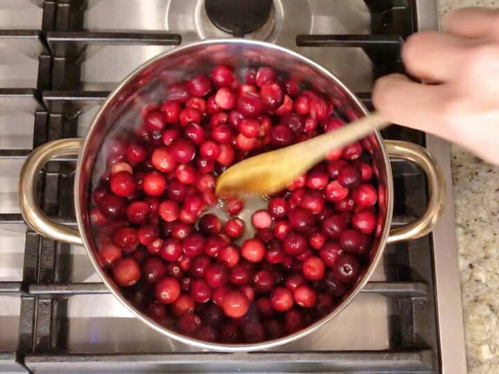 Adding cranberries to the saucepan.