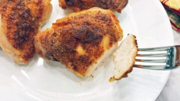 A baked chicken thigh is cut to show it's done.
