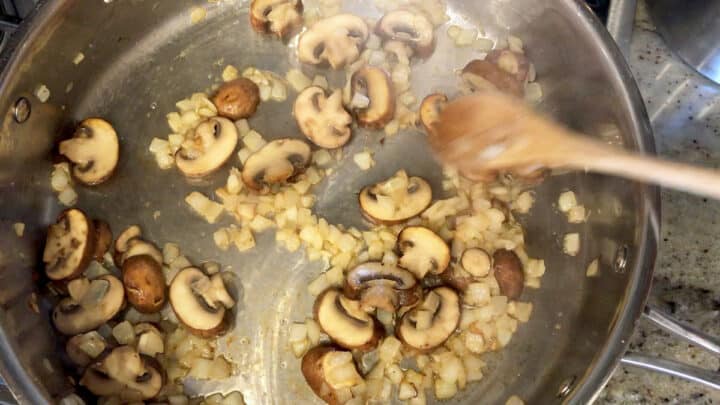 Cooking onions and mushrooms in a skillet.