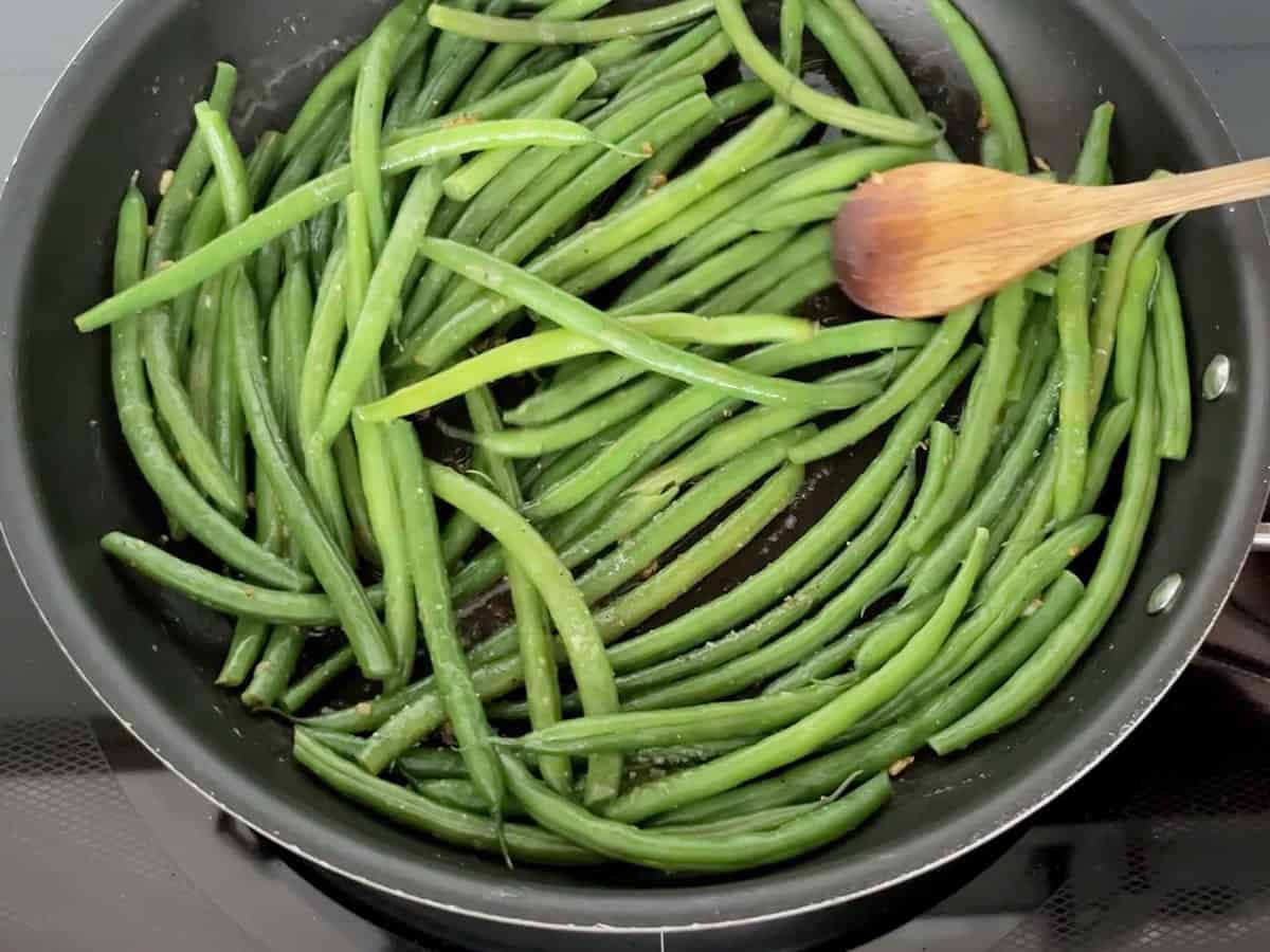 Adding the green beans to the skillet.