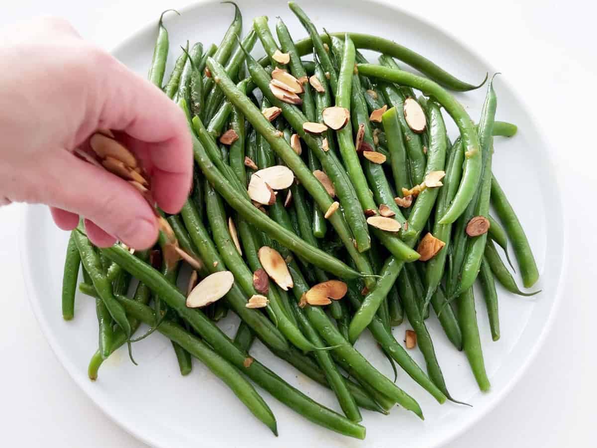 Topping the green beans with toasted almonds.
