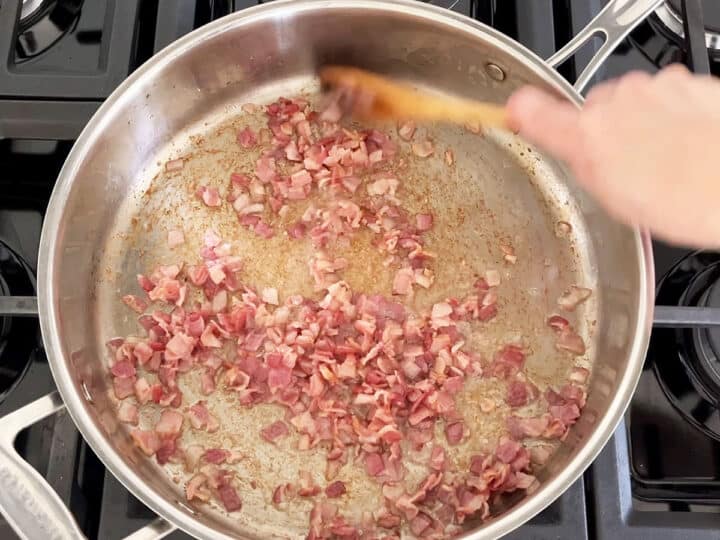 Cooking chopped bacon in a skillet.
