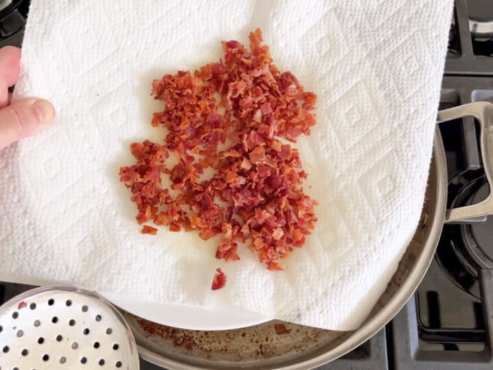 Cooked chopped bacon is placed on paper towels.
