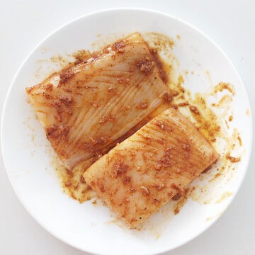 Two halibut fillets coated with an olive oil and spice mixture.