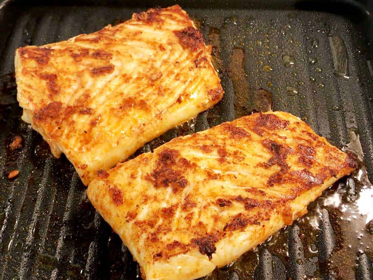 Two fillets perfectly grilled halibut in a grill pan. 