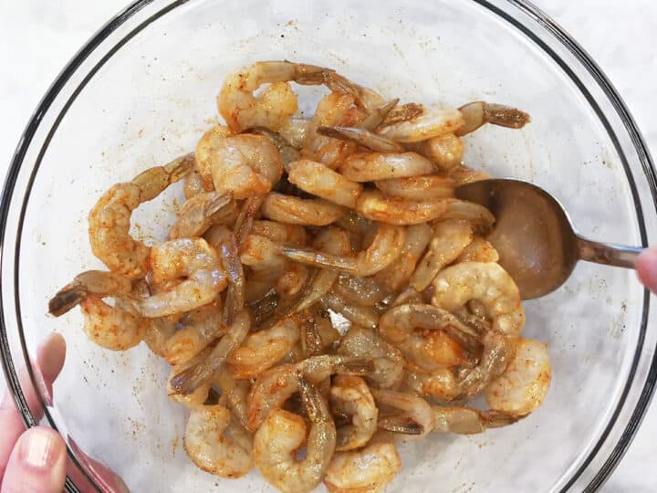 Coating shrimp with oil and spices.