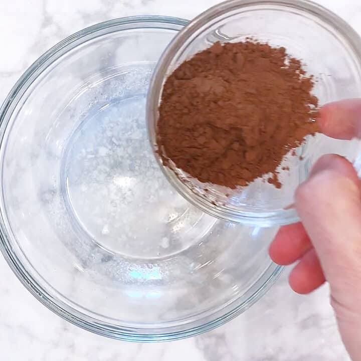 Adding cocoa powder to melted coconut oil.