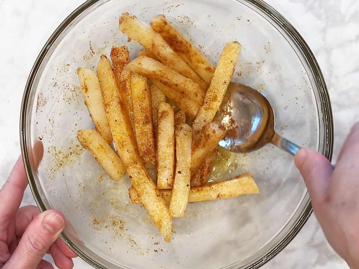 Coating jicama fries with olive oil and spices. 