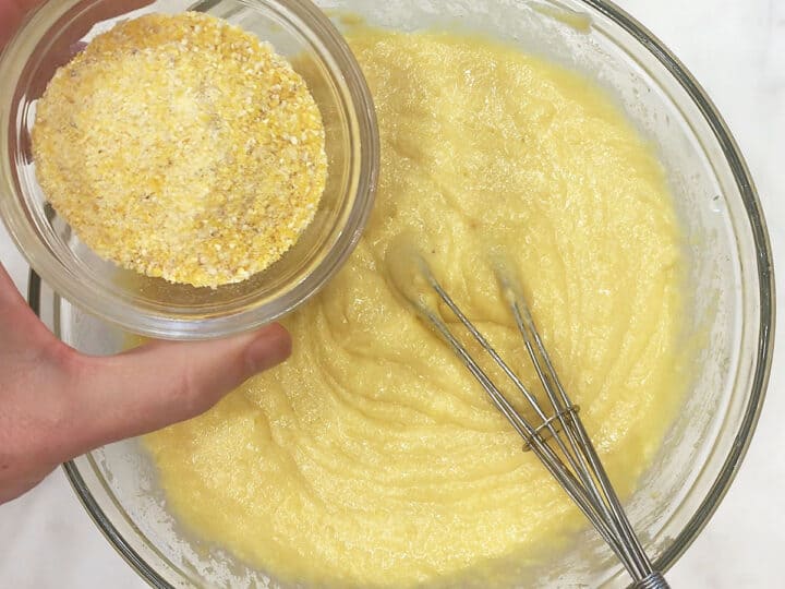 Adding cornmeal to the batter in the bowl.