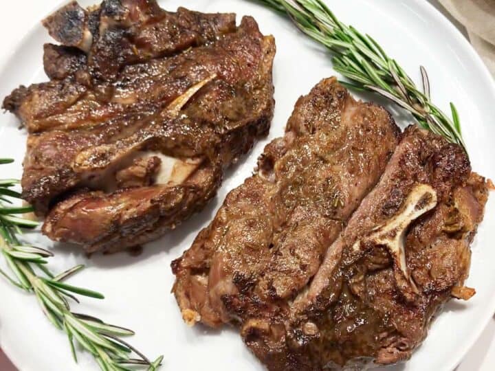 The chops are served on a plate, garnished with rosemary leaves.