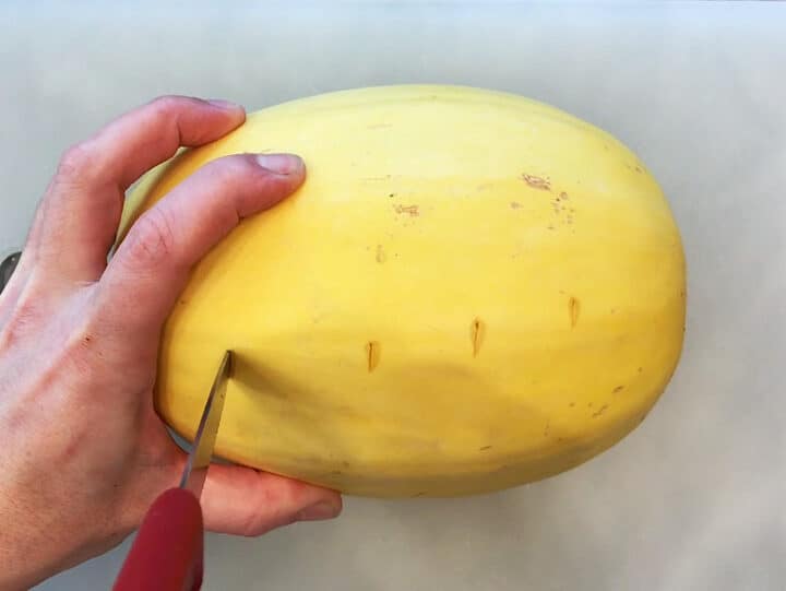 Piercing the spaghetti squash with a knife.
