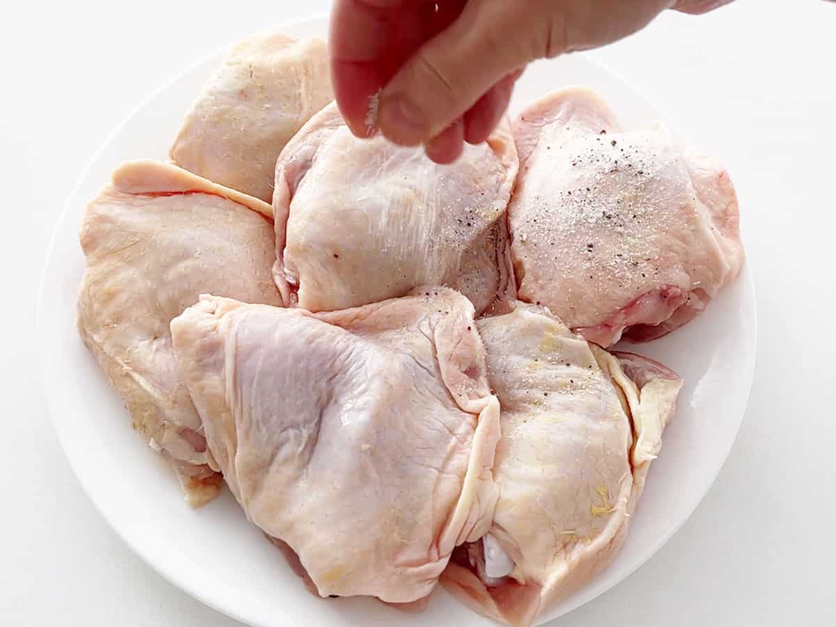 Seasoning the chicken with salt and pepper.