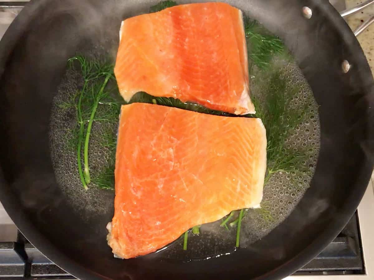 Adding salmon to the skillet. 