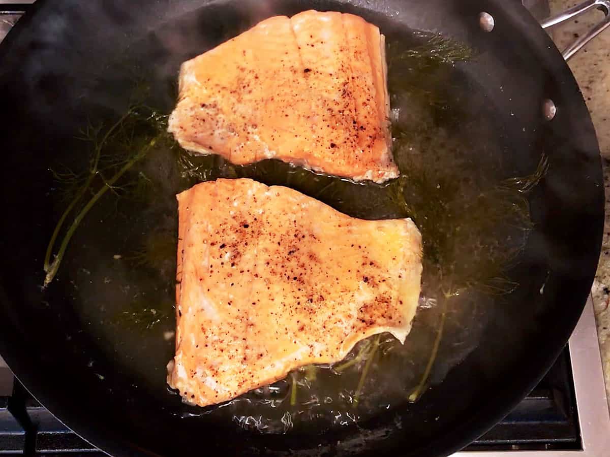 Uncovering the skillet; the poached salmon is ready. 