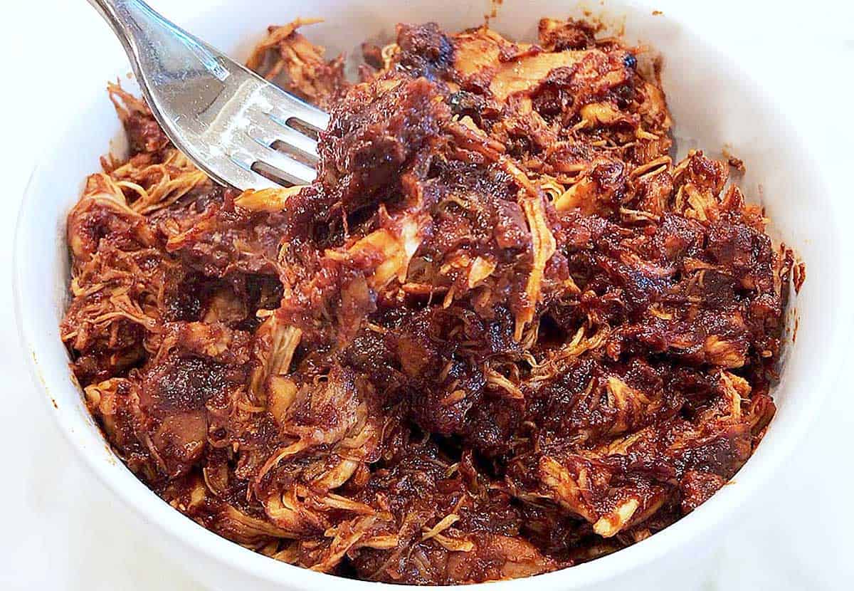 Pulled chicken is served in a white bowl. 