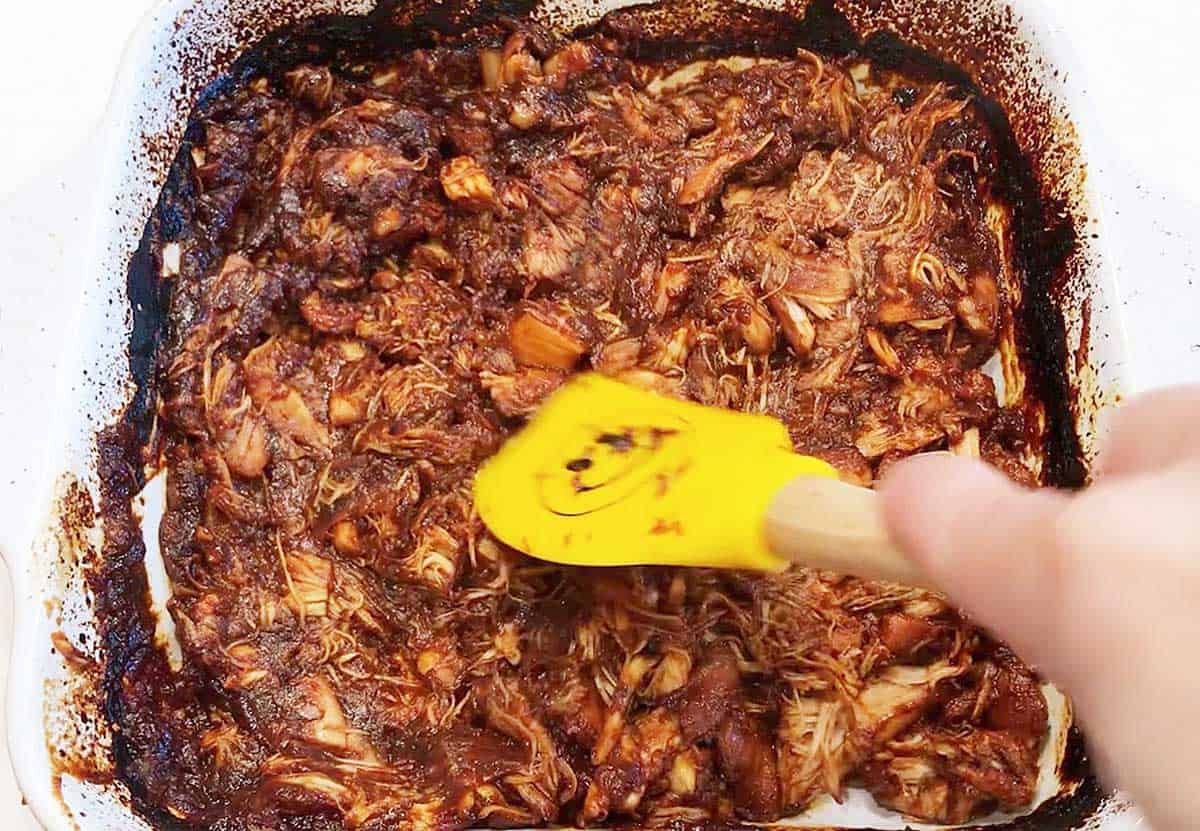 Shredding the pulled chicken in the pan. 